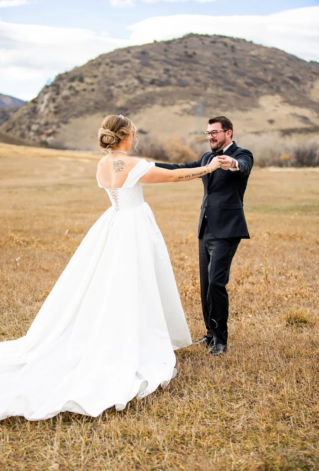 Bride and groom dancing in a mountain field